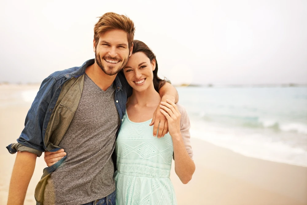 Smiling couple standing together at the beach