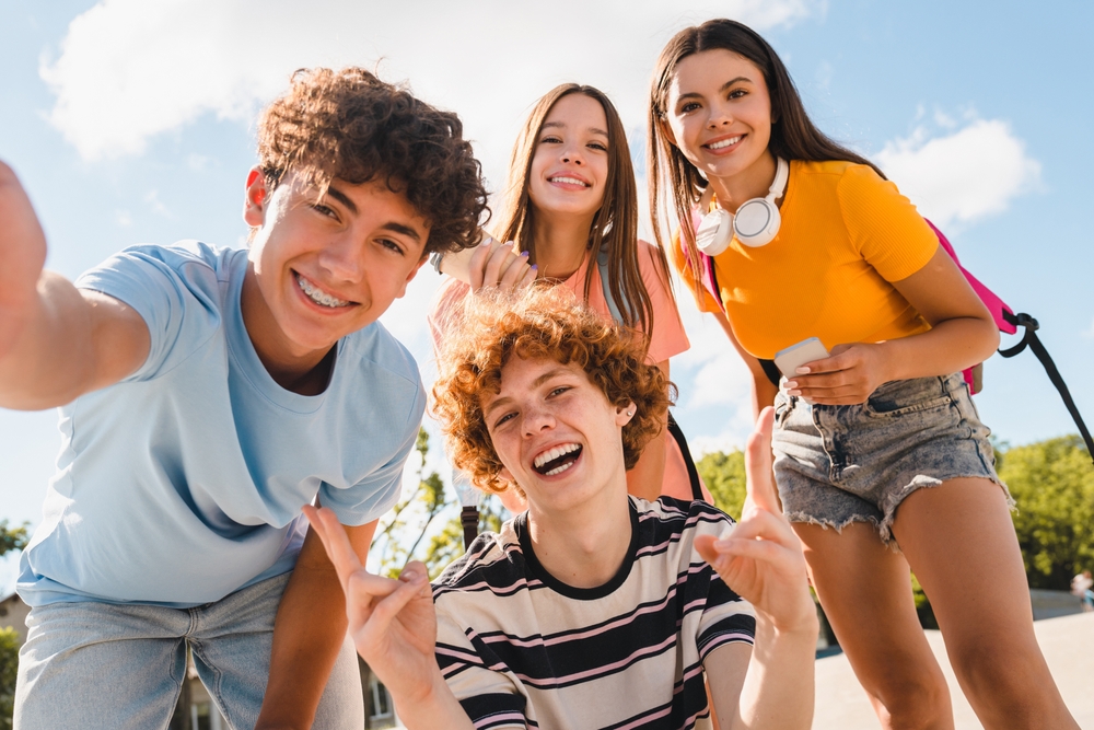 Four teenagers smiling together outdoors