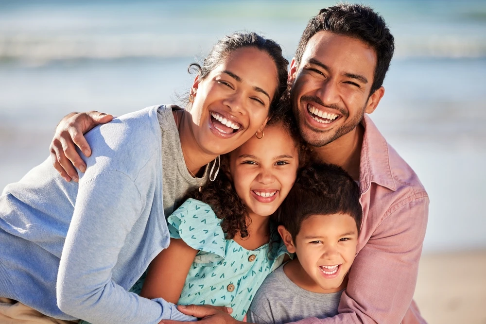 Two parents and two children smiling together at the beach